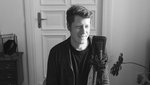 Foto von Felix Bießmann am Mikrofon mit einer Tür im Hintergrund während der Podcast-Aufnahme